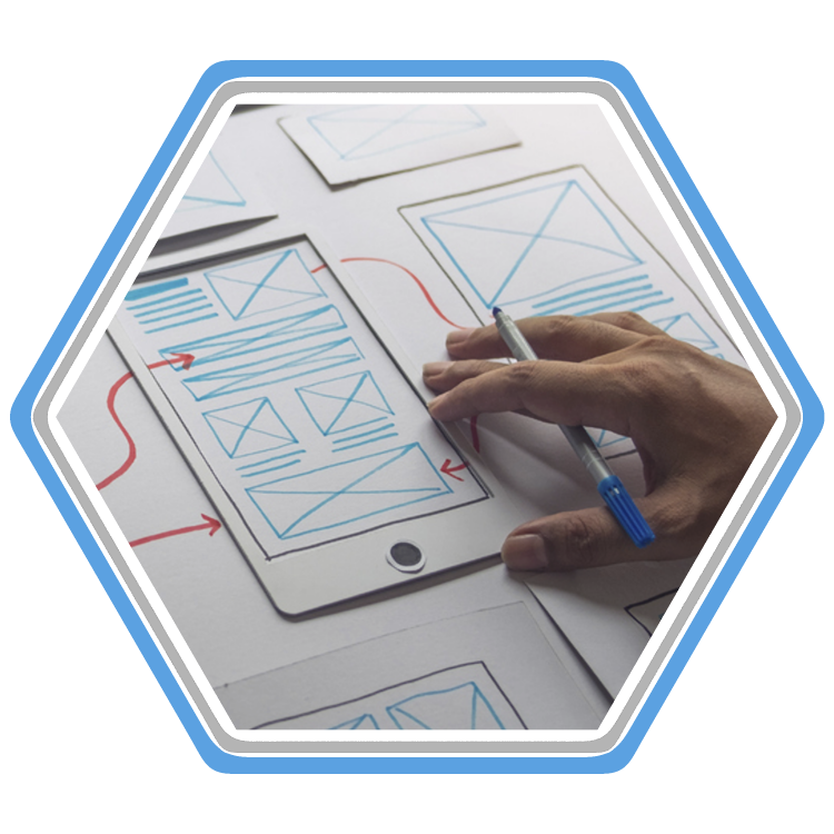 A hand rests on cardboard and paper mockups of a user interface design